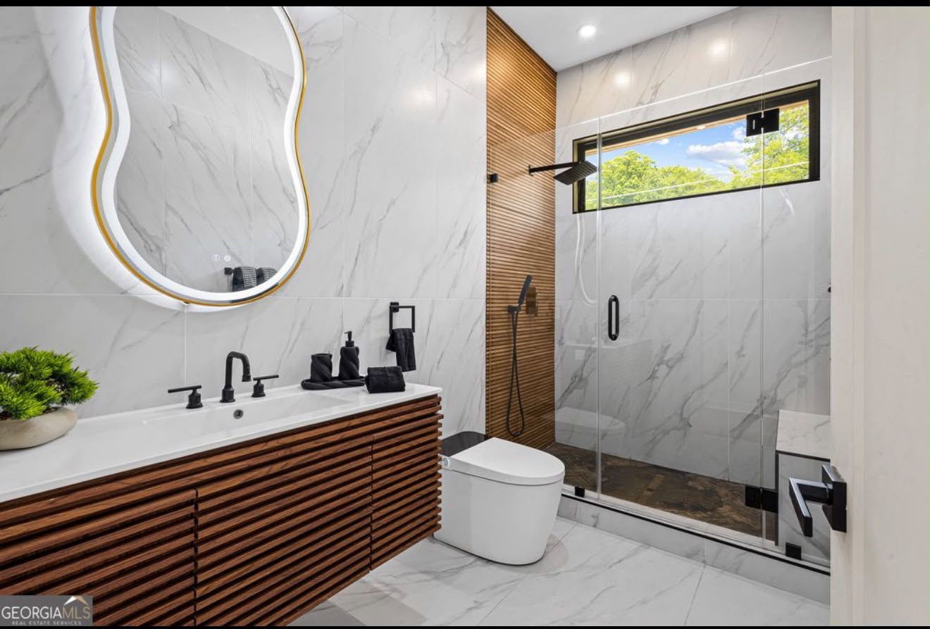 Luxury bathroom with book-matched marble walls and a vertical walnut slat accent