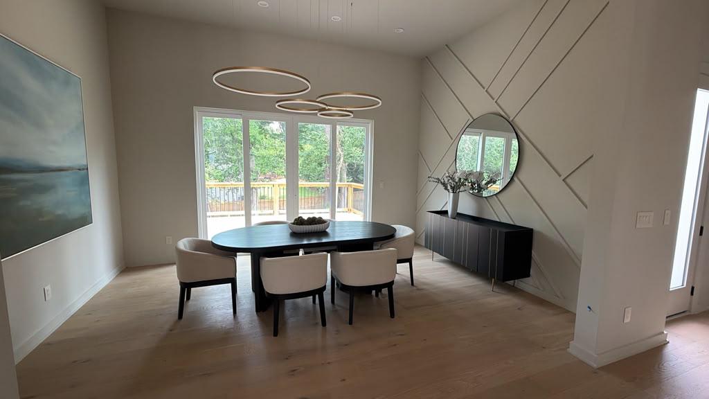 Dining room with geometric molding wall, round mirror and stacked ring chandeliers