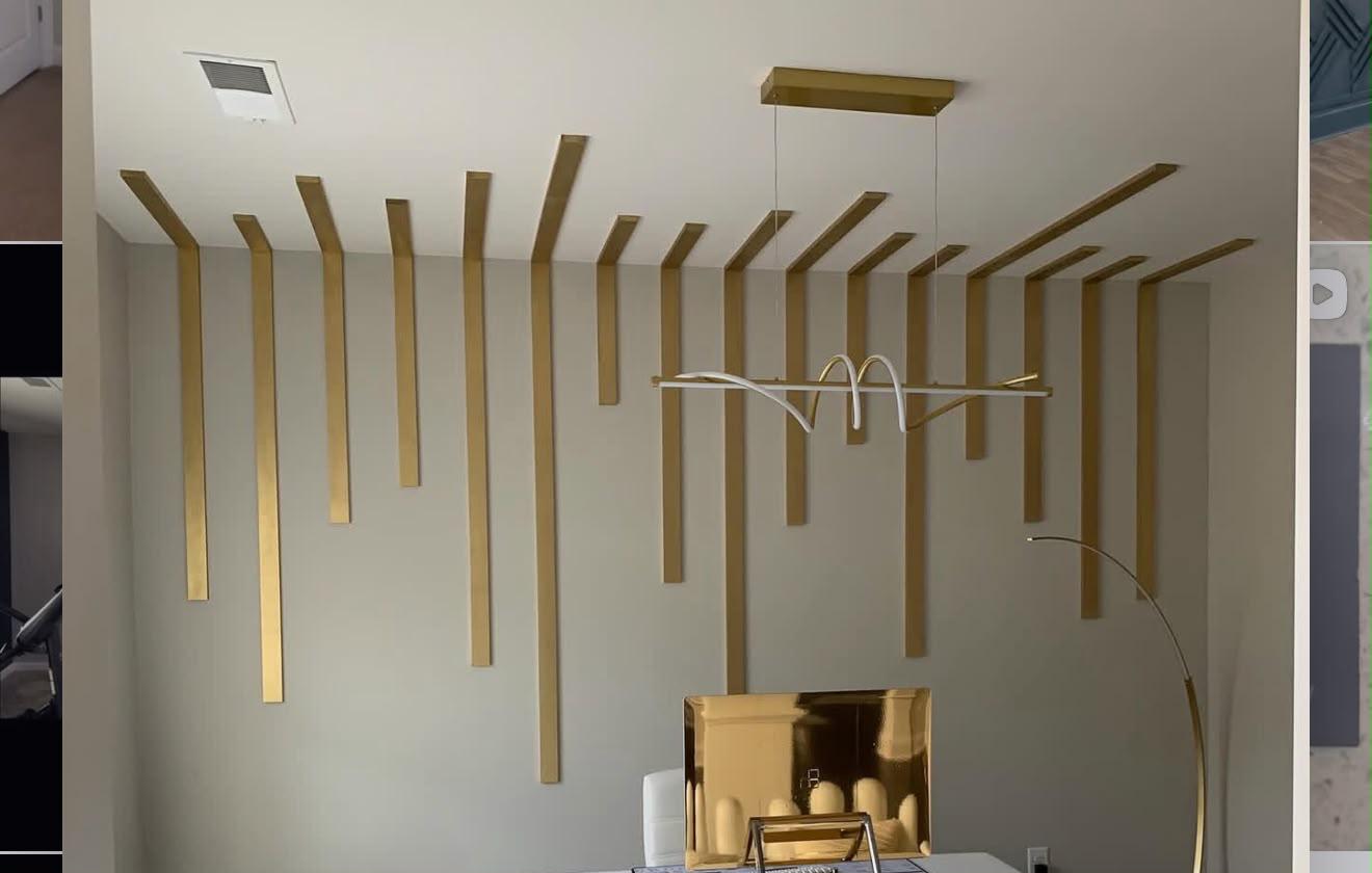 Modern office with sculptural brass ceiling slats and a linear pendant