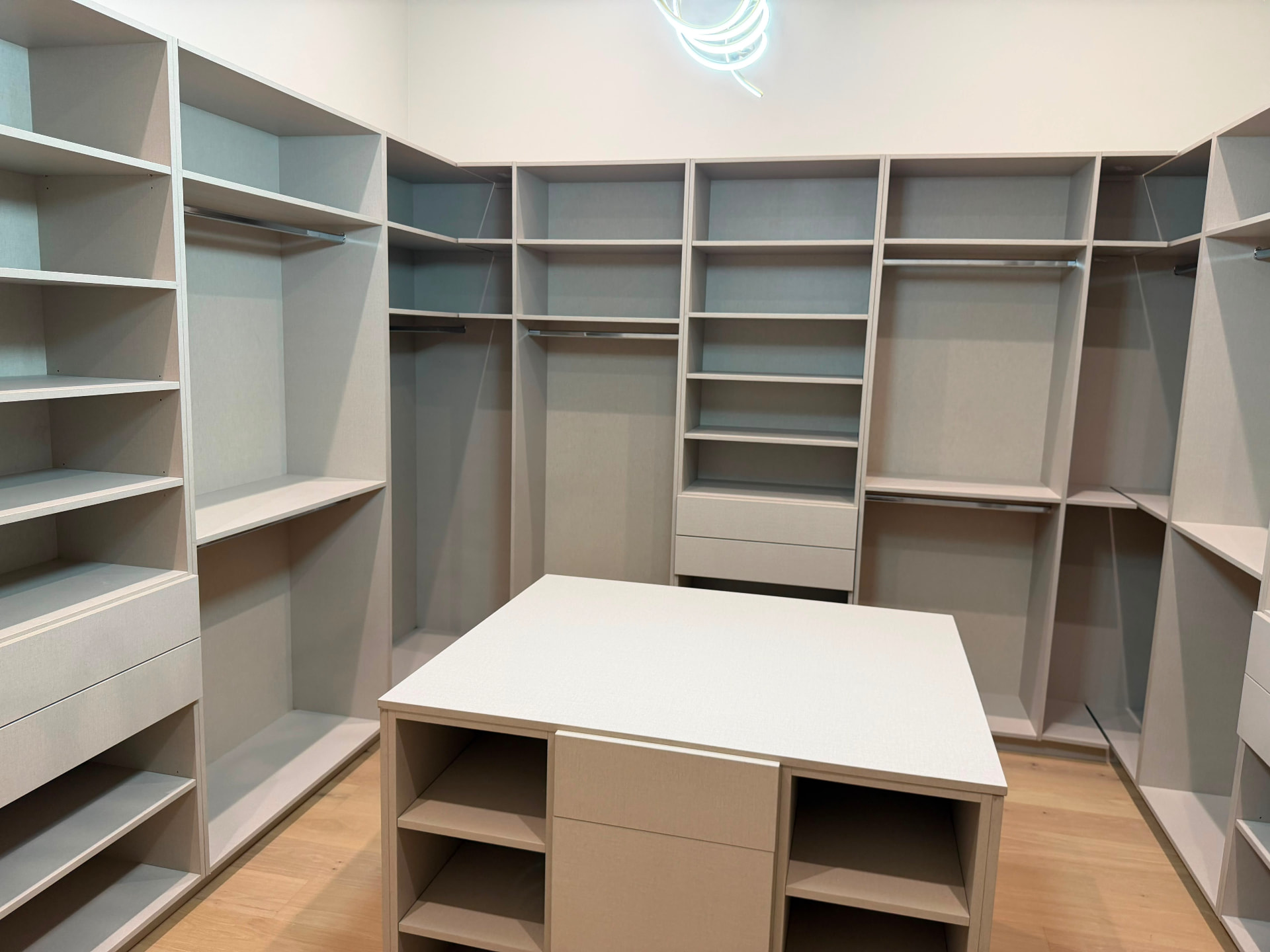 Symmetrical his and hers custom closet layout with island and neon ring light fixture