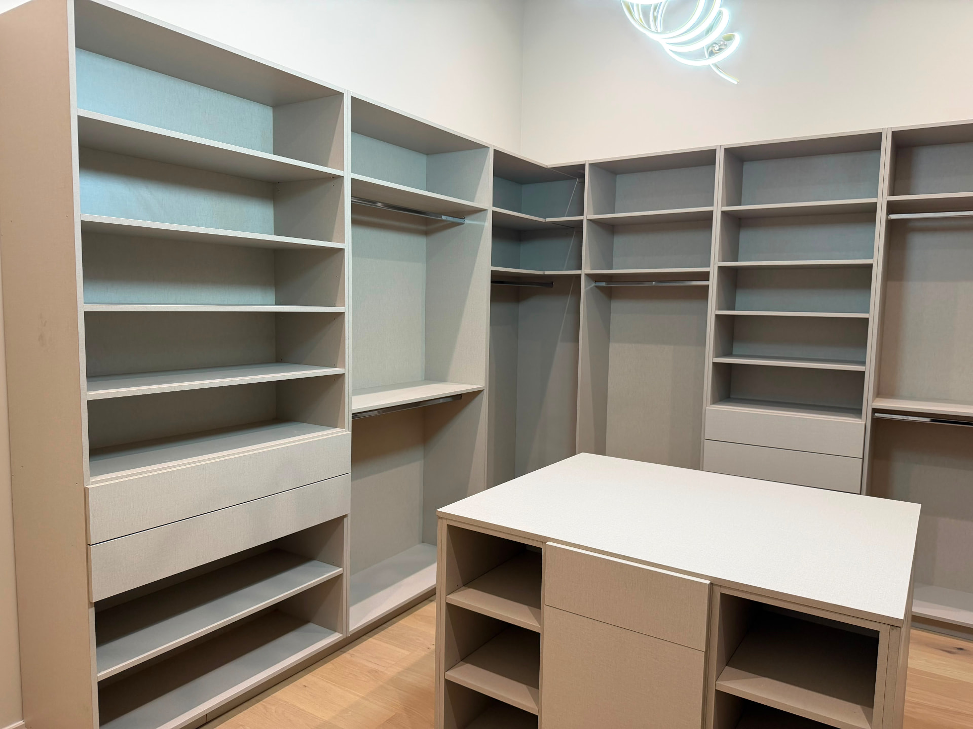 Completed custom walk-in closet suite with island, hanging sections and shelf towers